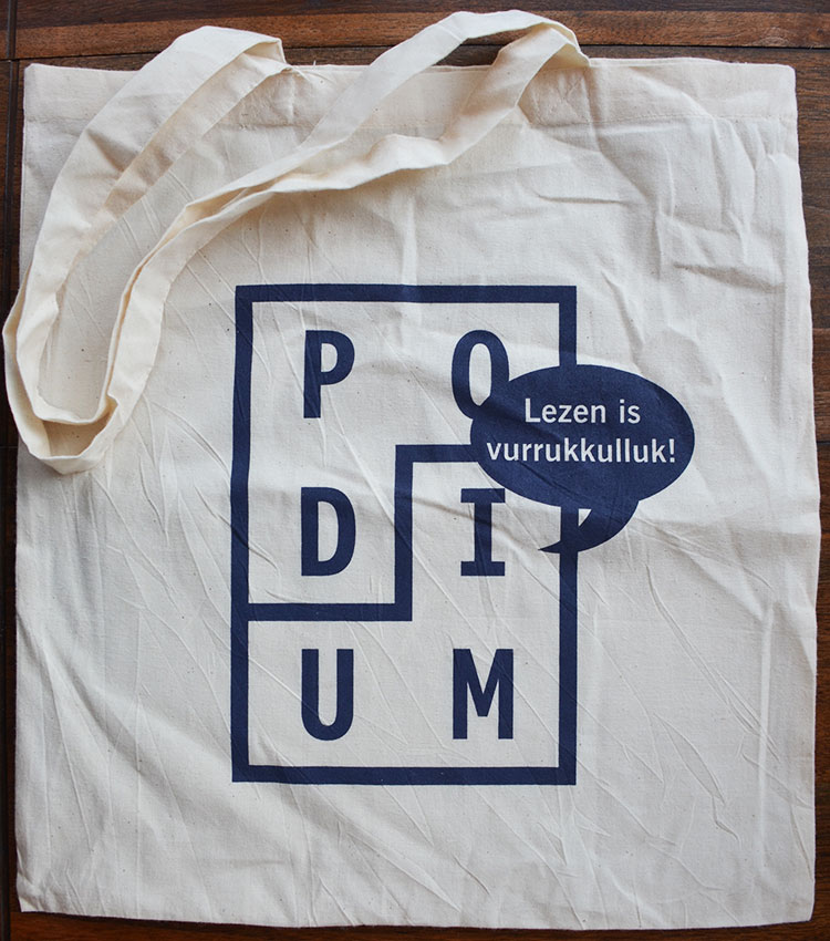 Tas ter promotie van Uitgeverij Podium (Joost Nijsen) en het kookboek Vurrukkulluk van Ronald Giphart & Mascha Lammes. Op de poster staat Lezen is Vurrukkulluk
